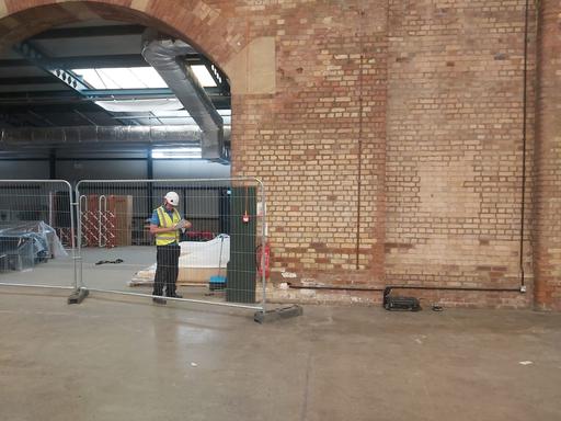 VMS Engineer standing inside the National Railway Museum under a arch checking vibration monitoring equipment using a iPad.